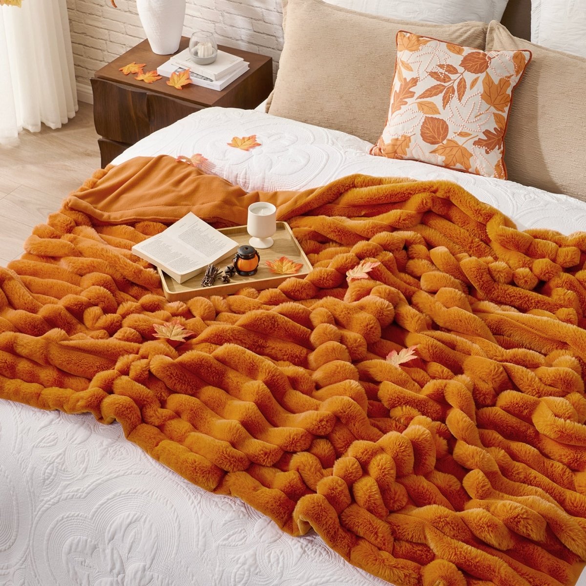 Orange blanket draped over a bed with a tray of items on a nightstand.  #color_Burnt Orange
