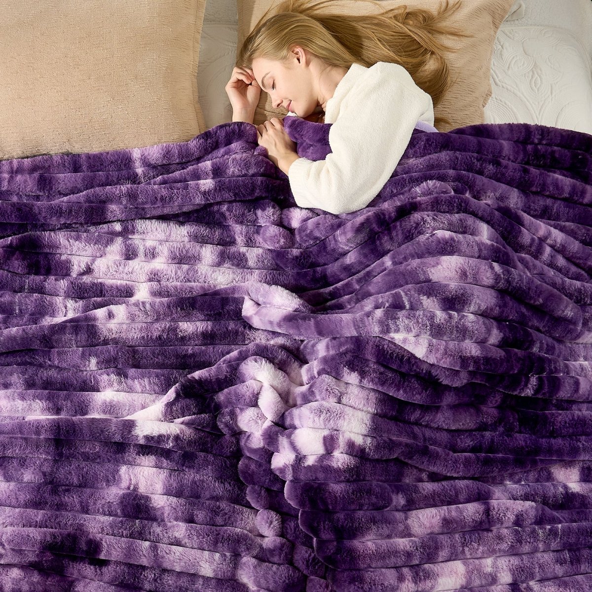 Woman lying under a purple blanket on a bed. #color_Tie-dye Purple