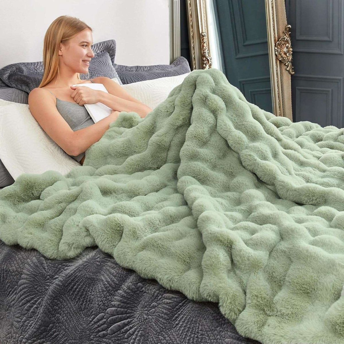 Woman wrapped in a sage green bubble faux fur blanket on a bed #color_Sage Green
